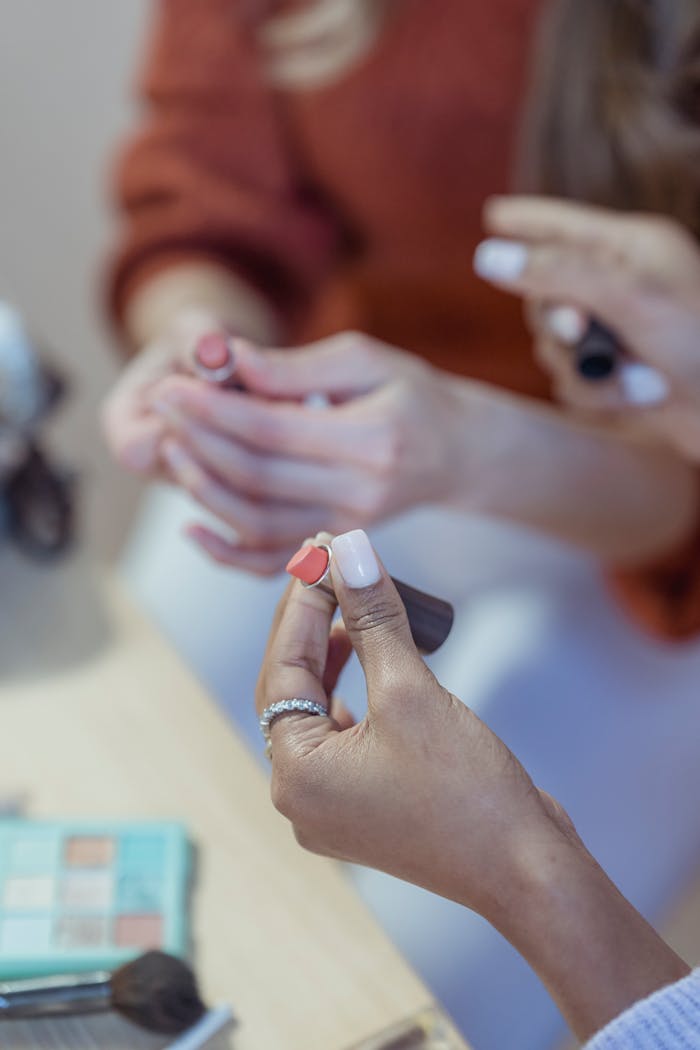 our-story From above of crop anonymous multiethnic women showing lipsticks to each other on blurred background