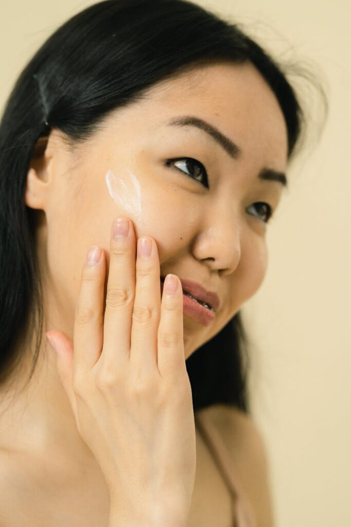 A woman applying face cream as part of her skincare routine, emphasizing self-care and natural beauty.